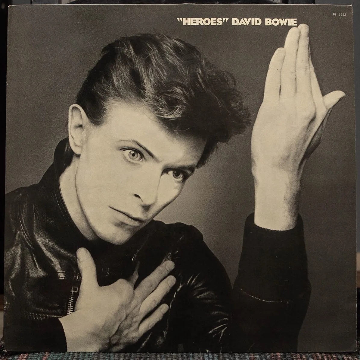 Front of David Bowie's "Heroes" album, with a man in a black jacket raising his hand.