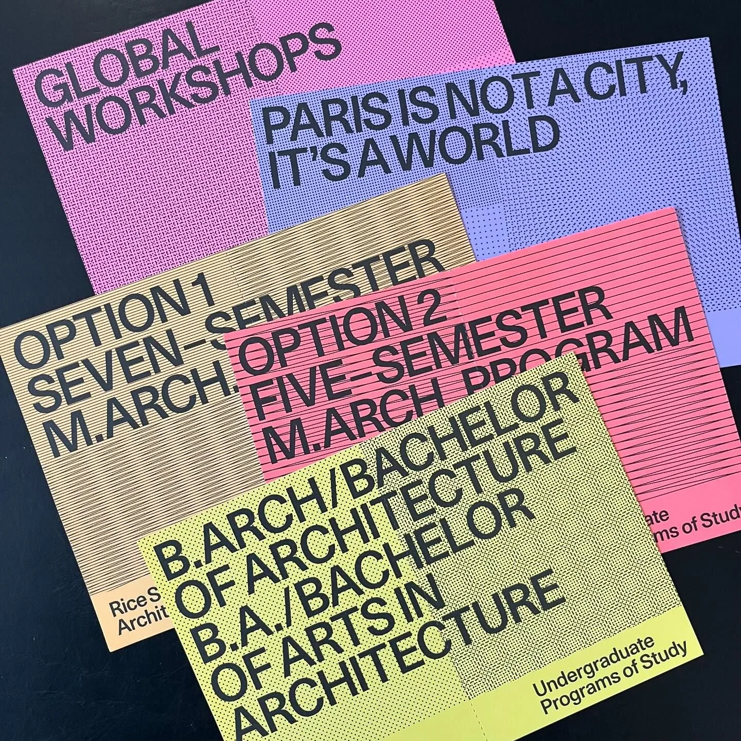 Five overlapping architecture programme cards in pink, lilac, tan, coral and yellow, each with large black capital letters and a fine halftone pattern, on a black table.