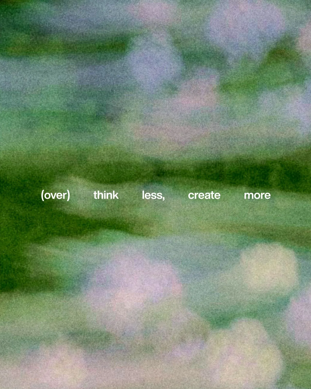 A soft, grainy, blurred photo of green foliage and pale lilac flowers, with the line '(over) think less, create more' in small white letters across the middle.